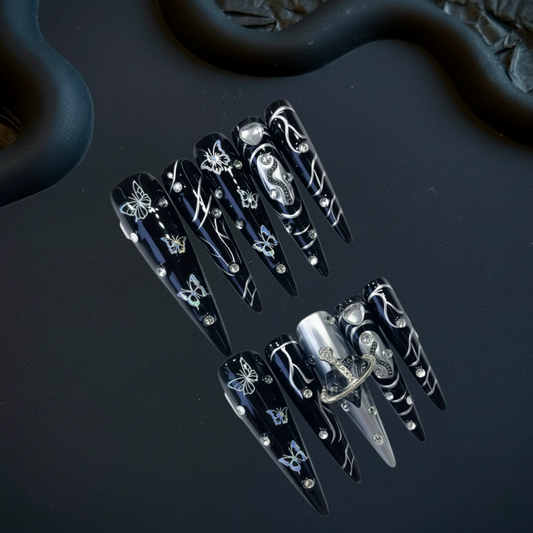 Black nail art designs with silver accents on a dark surface