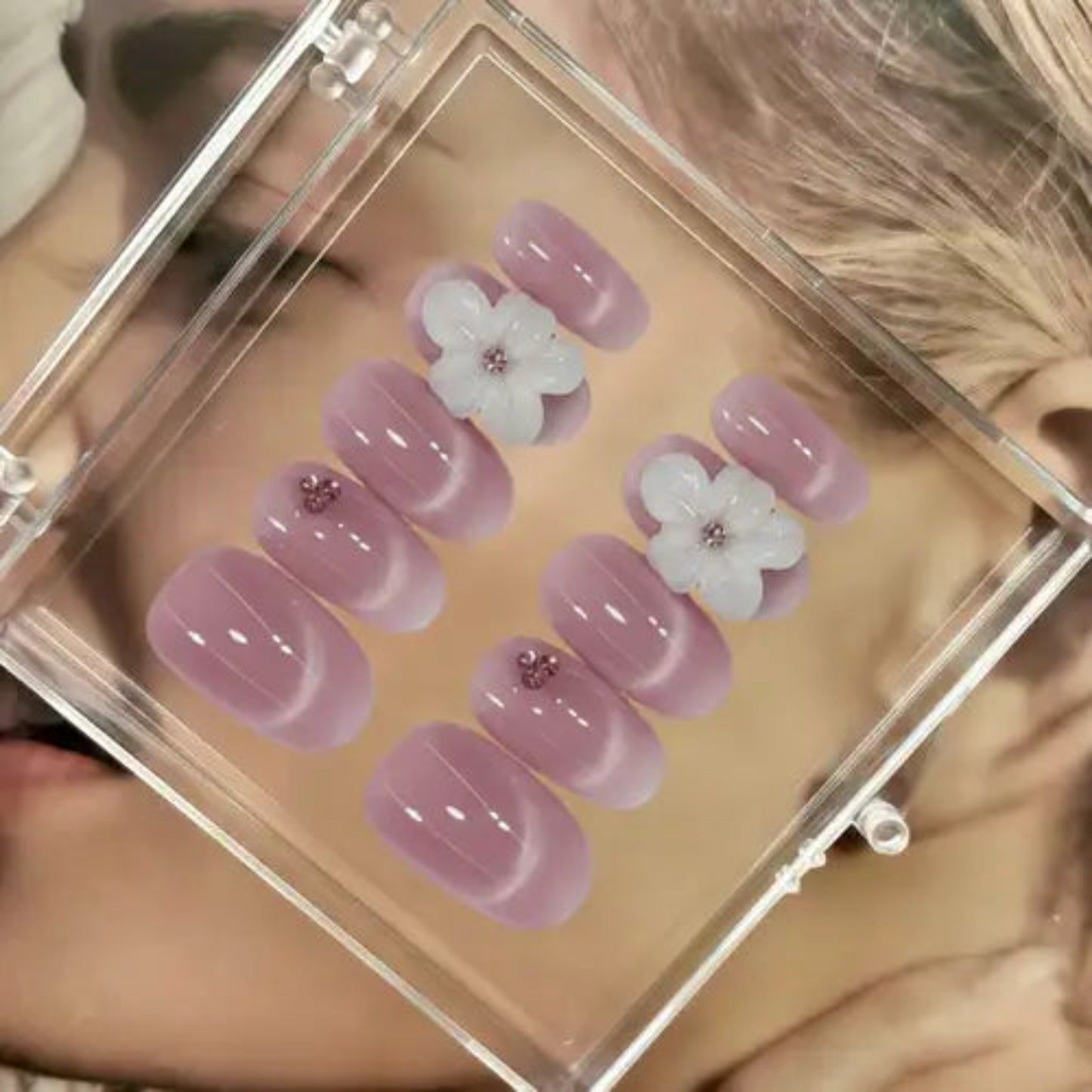 Set of pink nail art with floral designs in a clear display case.