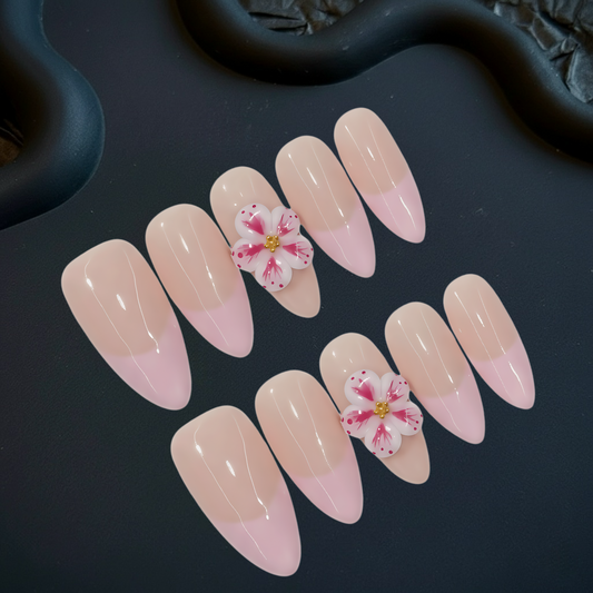 Nail art with pink and beige gradient and floral design on a dark background