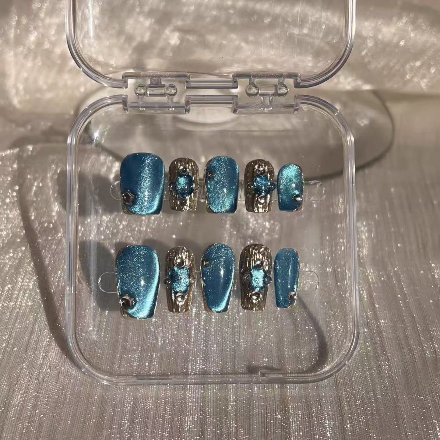 Hand with blue and silver nail design holding a white mug.