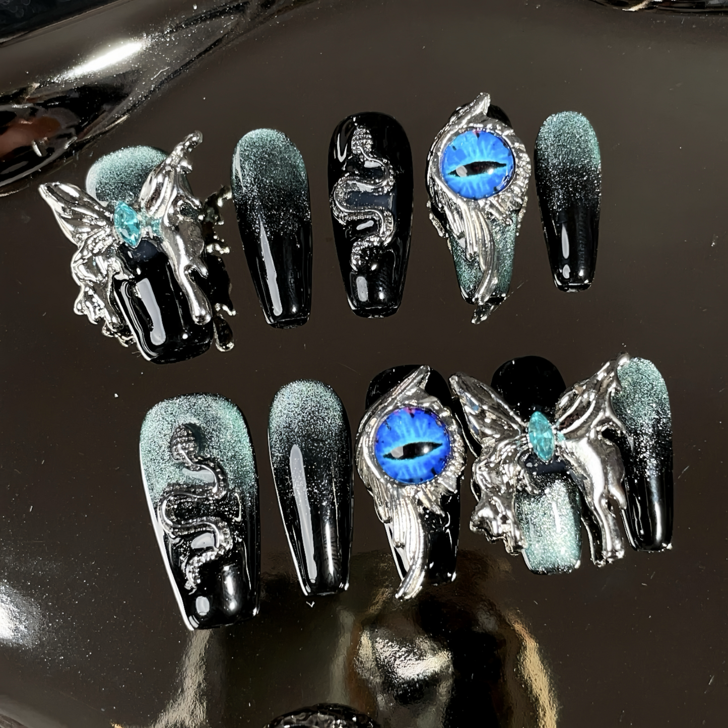 Decorative false nails with fantasy designs on a reflective surface