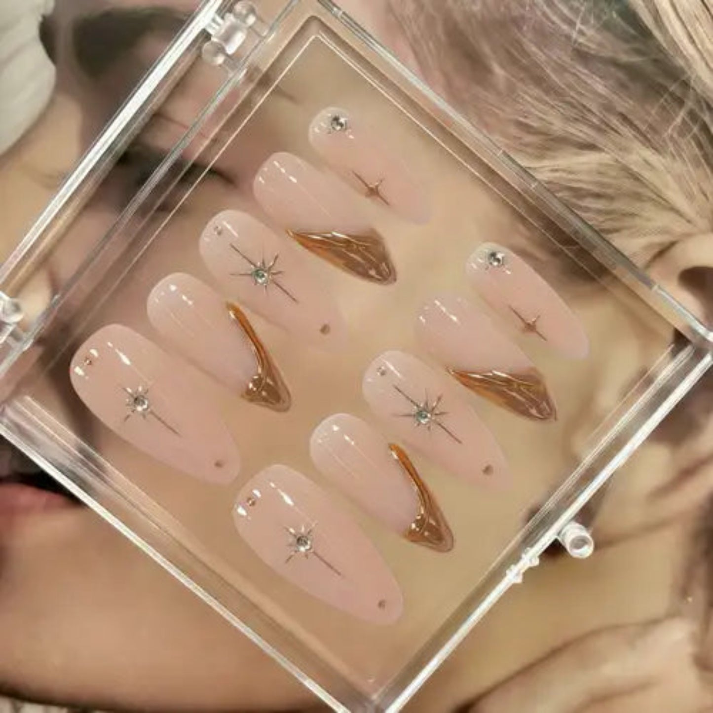 Set of decorative false nails with gold accents and rhinestones in a clear case.