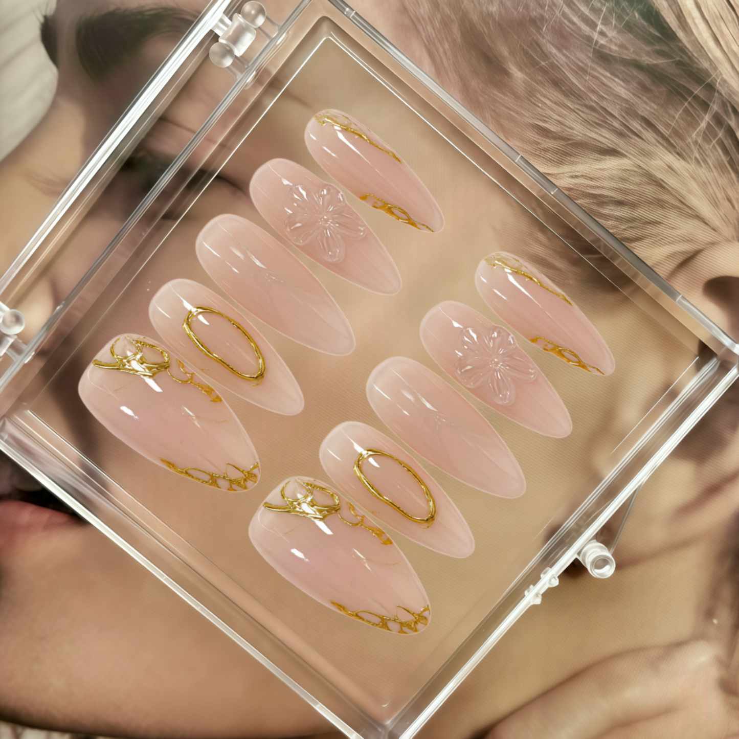 Set of pink press-on nails with gold accents in a clear case.