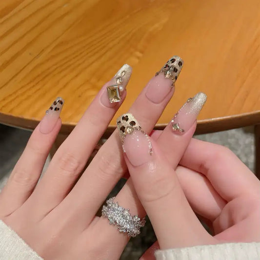 Close-up of hands with decorative nail art and a ring, against a wooden surface.