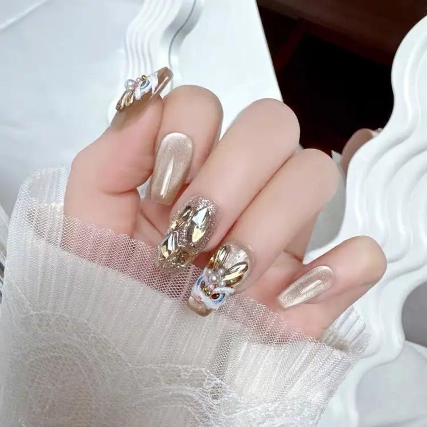 Hand with decorative nail art wearing a sheer white sleeve.