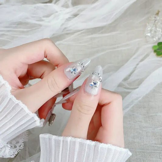 Close-up of hands with decorative nail art holding a clear nail extension.