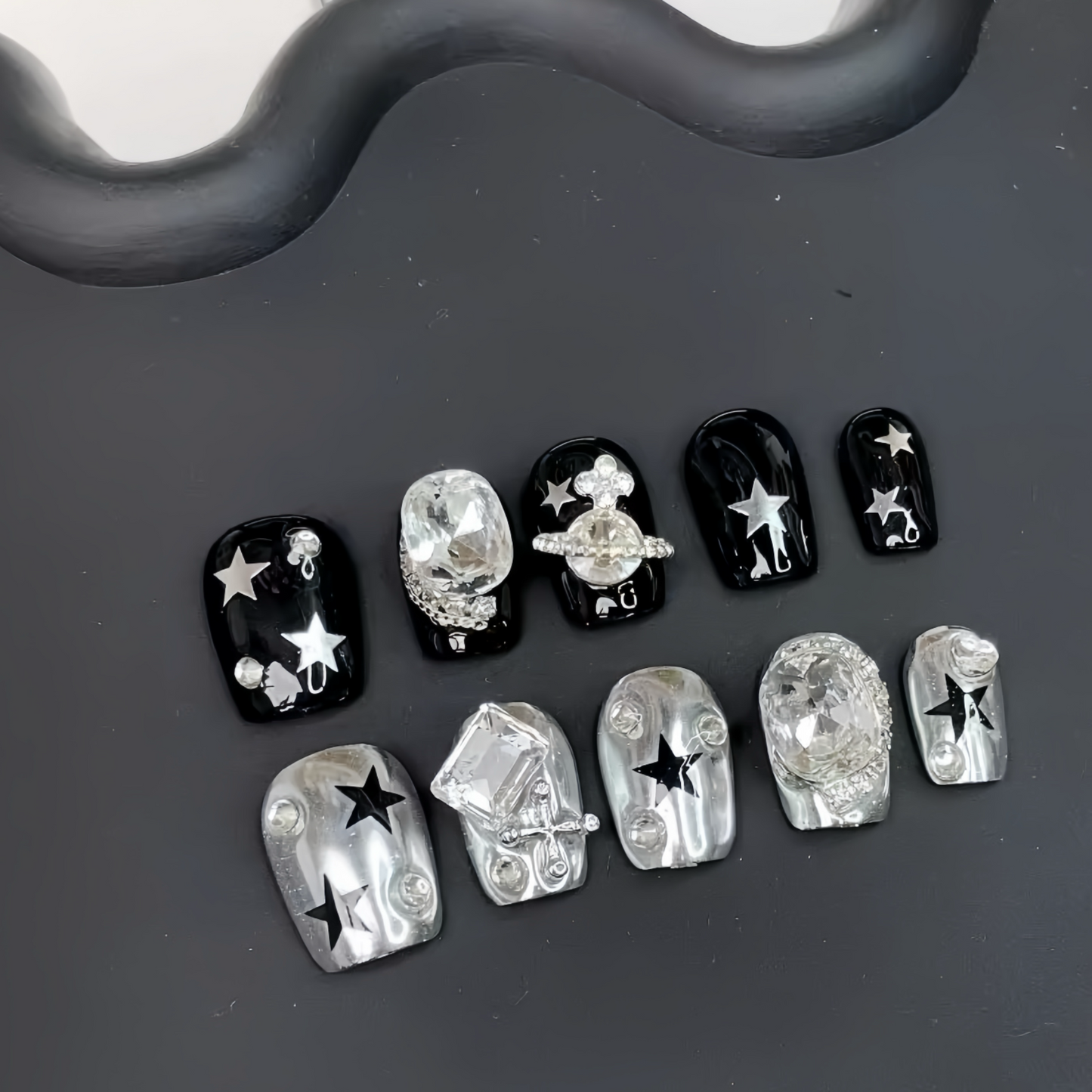 Set of black and silver nail art decorations on a dark surface