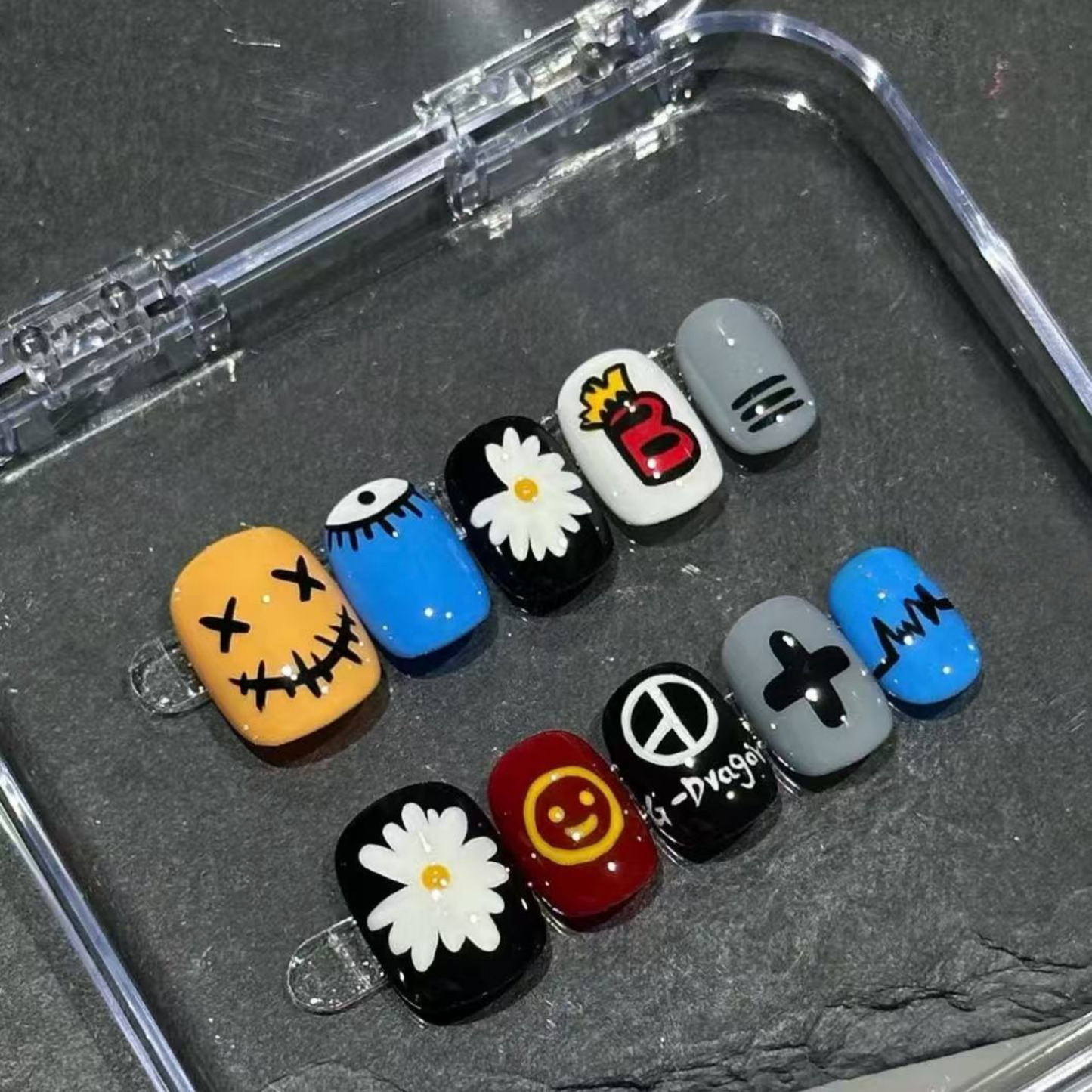 Set of colorful nail art designs in a clear case on a dark surface