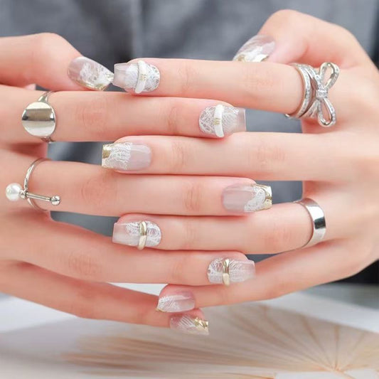 Close-up of hands with decorative nail art and multiple rings on a neutral background