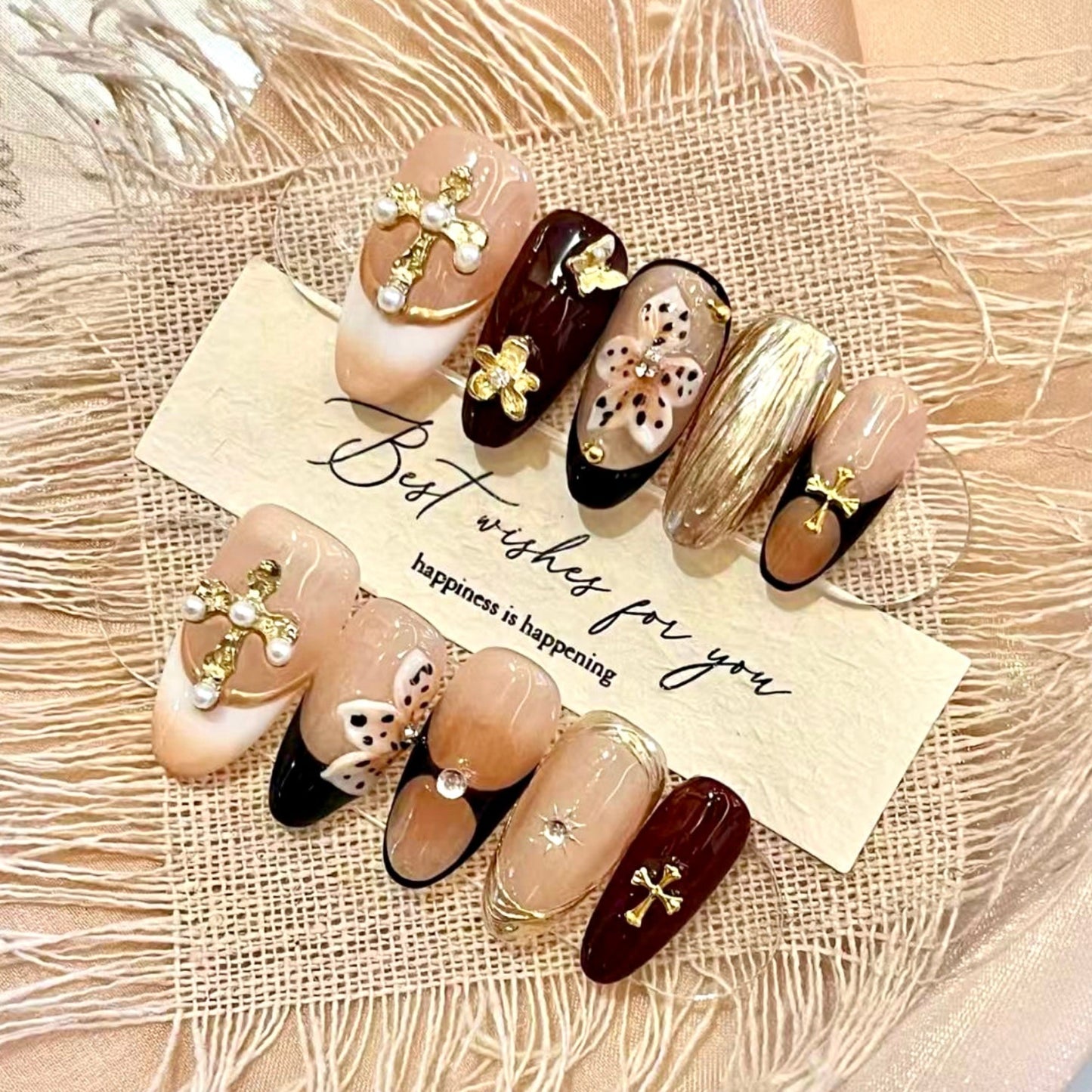 Decorative nail art set with gold accents on a textured beige surface
