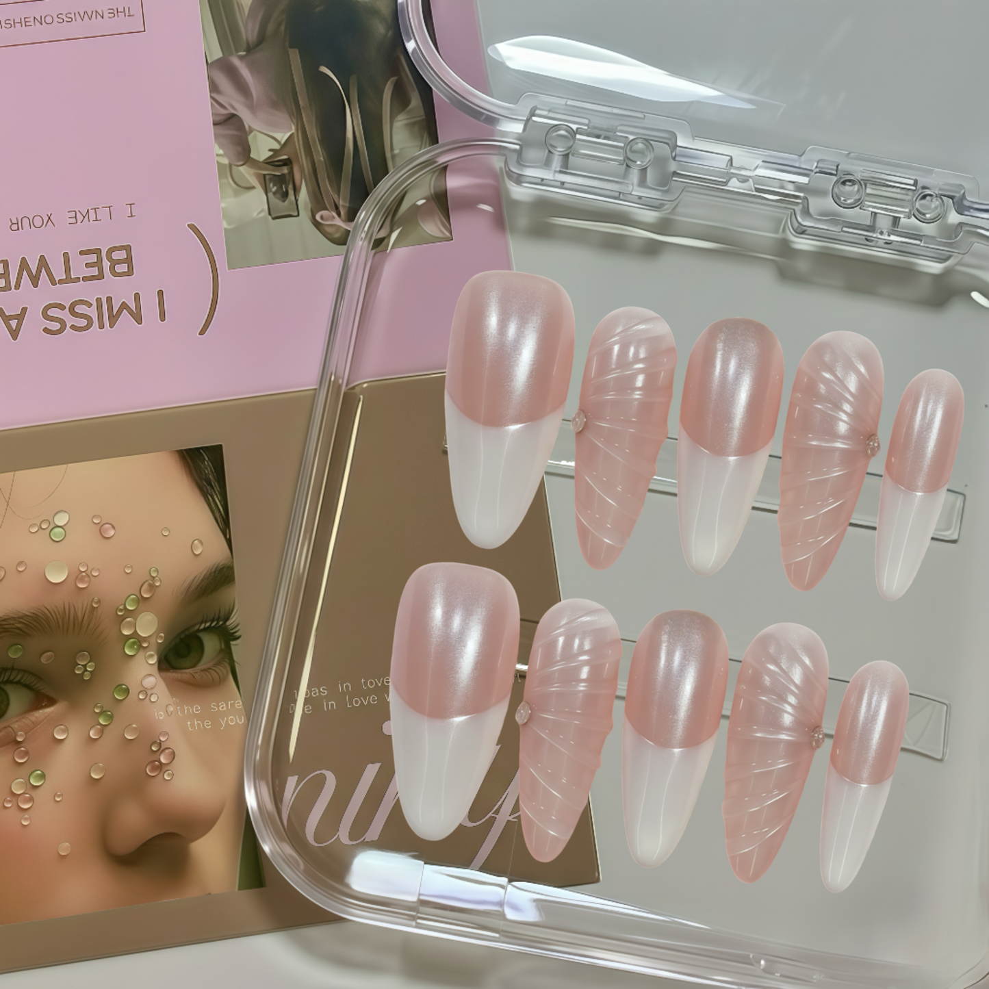 Set of pink and white false nails in a clear case with a magazine in the background.