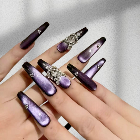 Purple and black nail designs with rhinestones on a neutral background