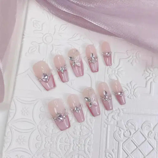 Set of pink nail designs with decorative elements on a textured white surface.