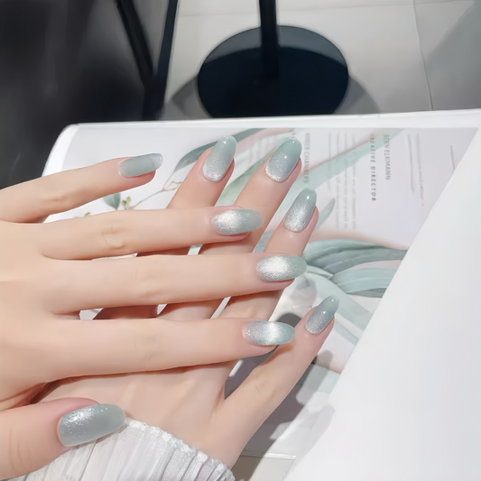 Hand with silver glittery nail polish on a magazine background