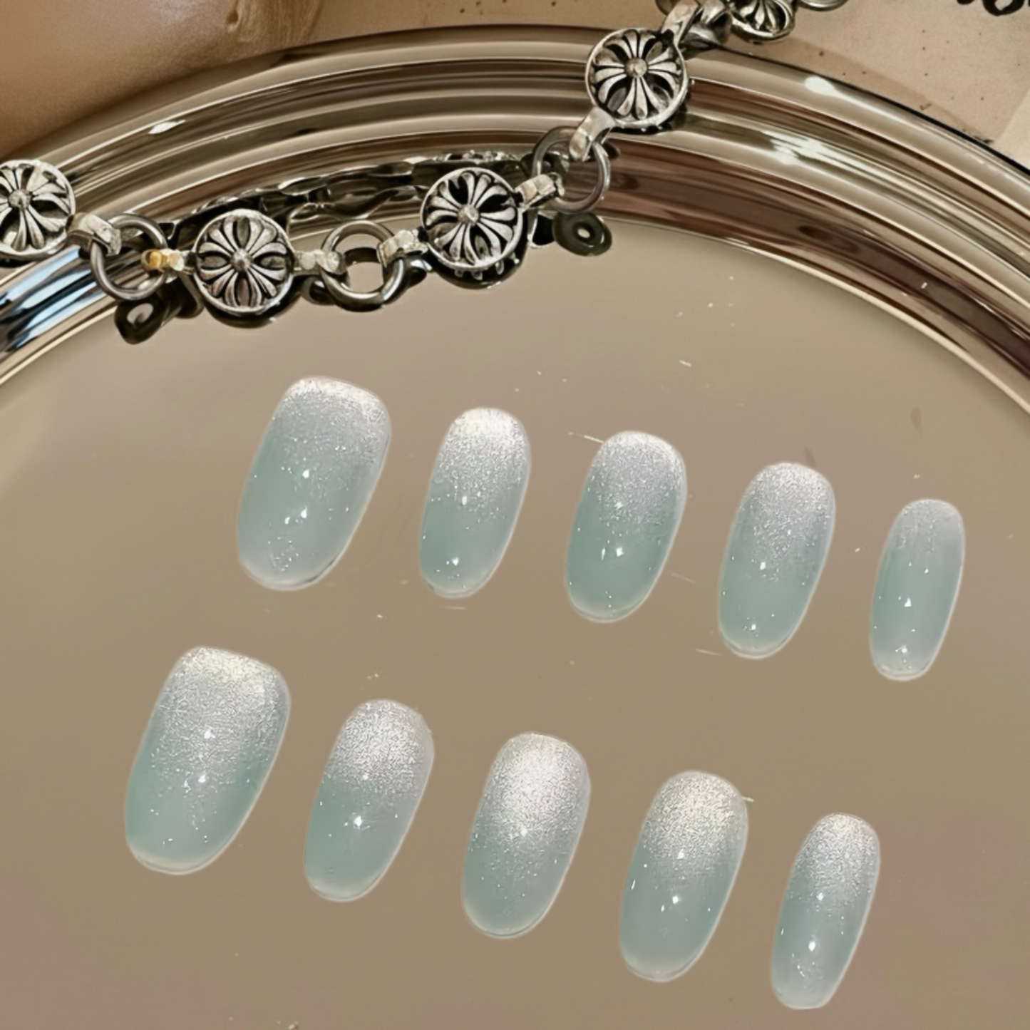 Nail polish color swatches with a silver bracelet on a neutral background