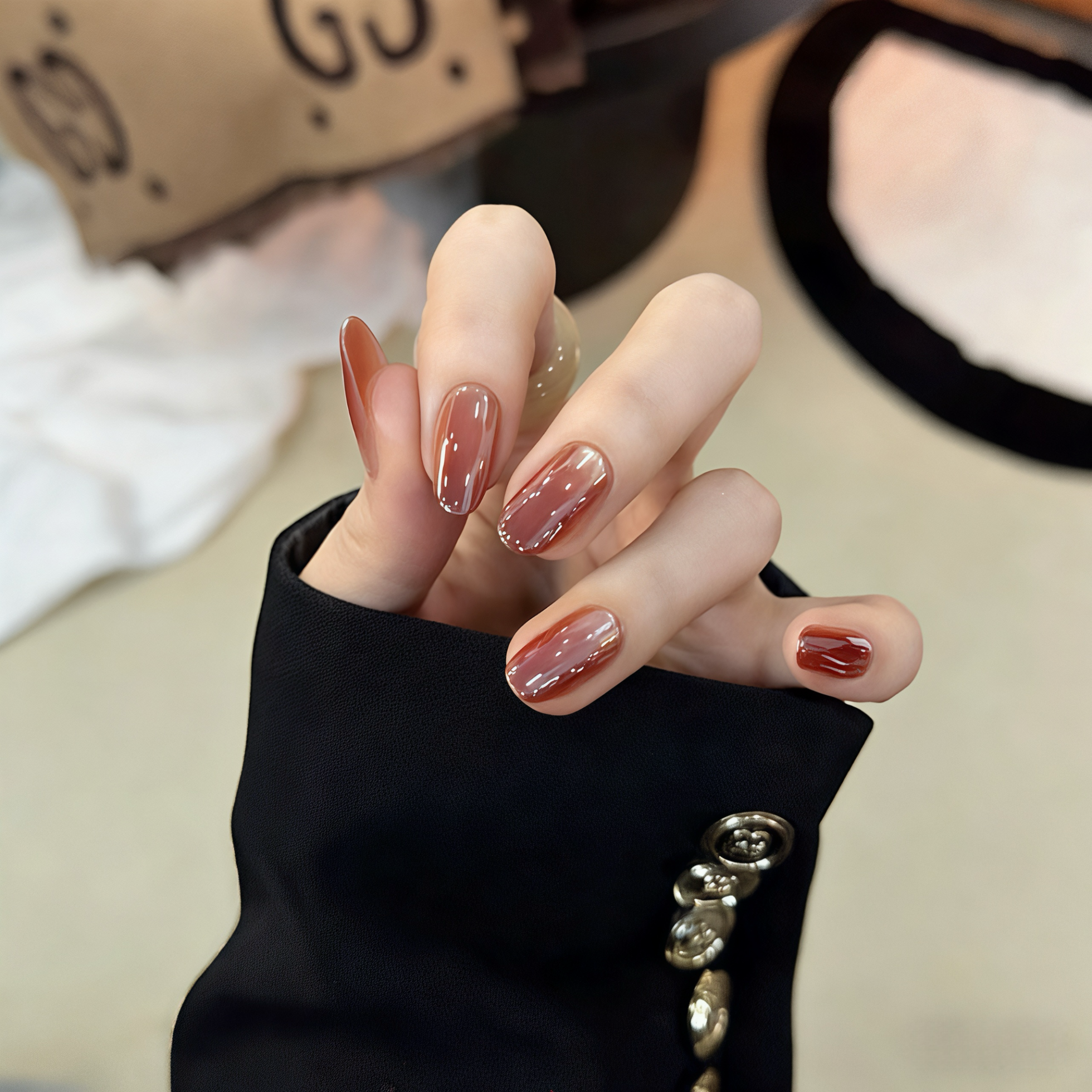 Close-up of a hand with polished nails wearing a black jacket.