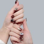 Close-up of hands with a gradient nail design on a gray background