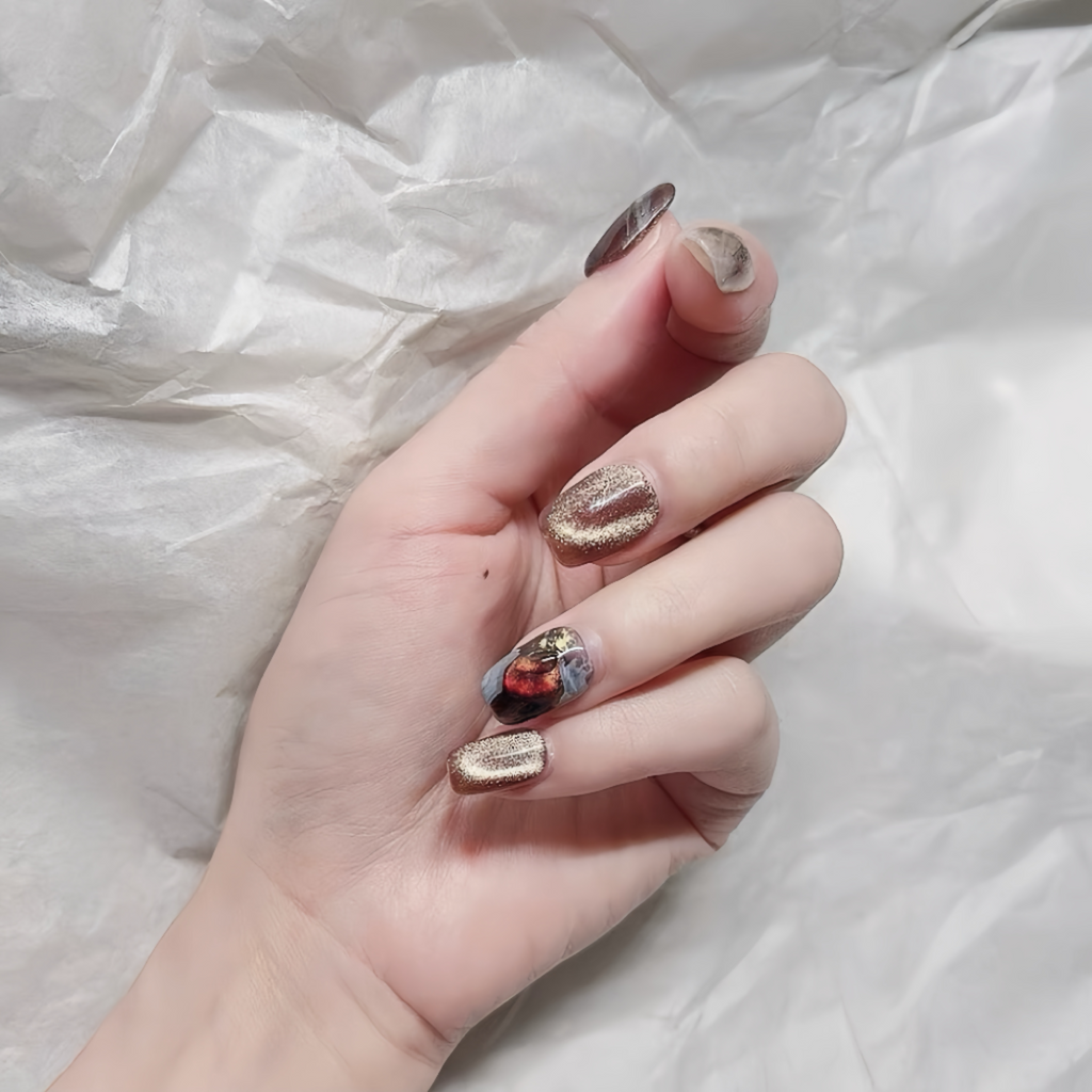 Hand with decorative nail art on a white fabric background