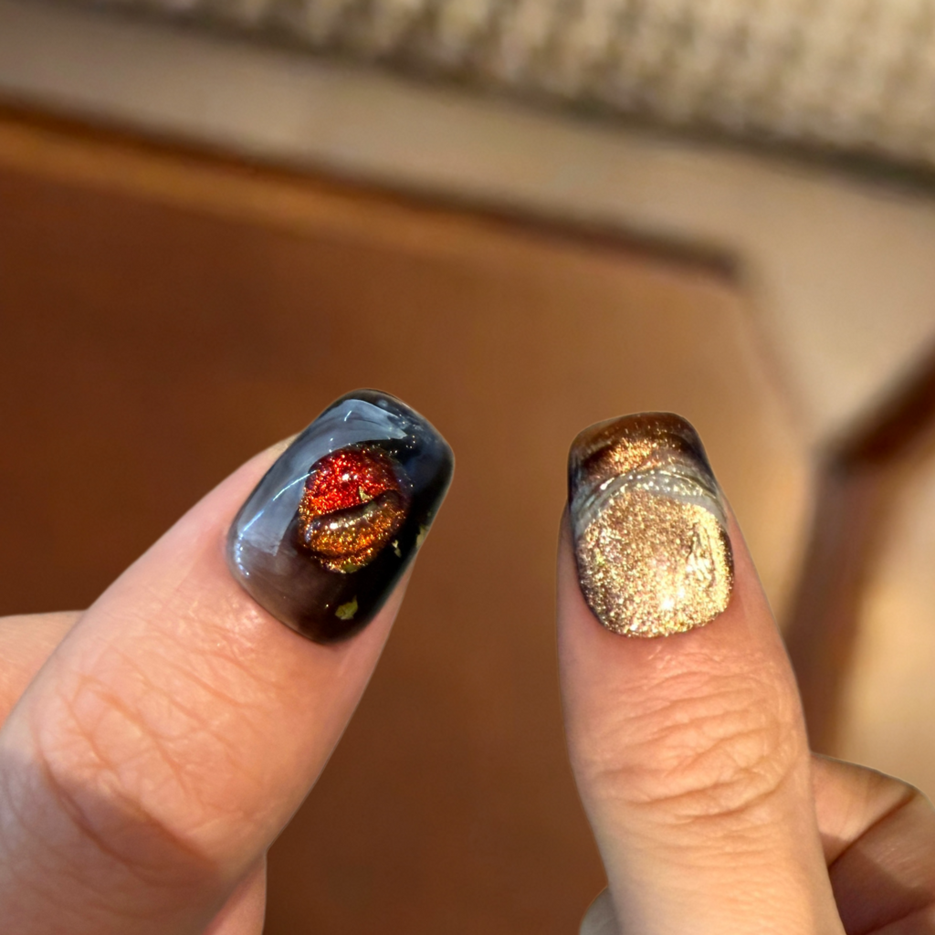 Close-up of two fingers with nail art, one with a galaxy design and the other with gold glitter.