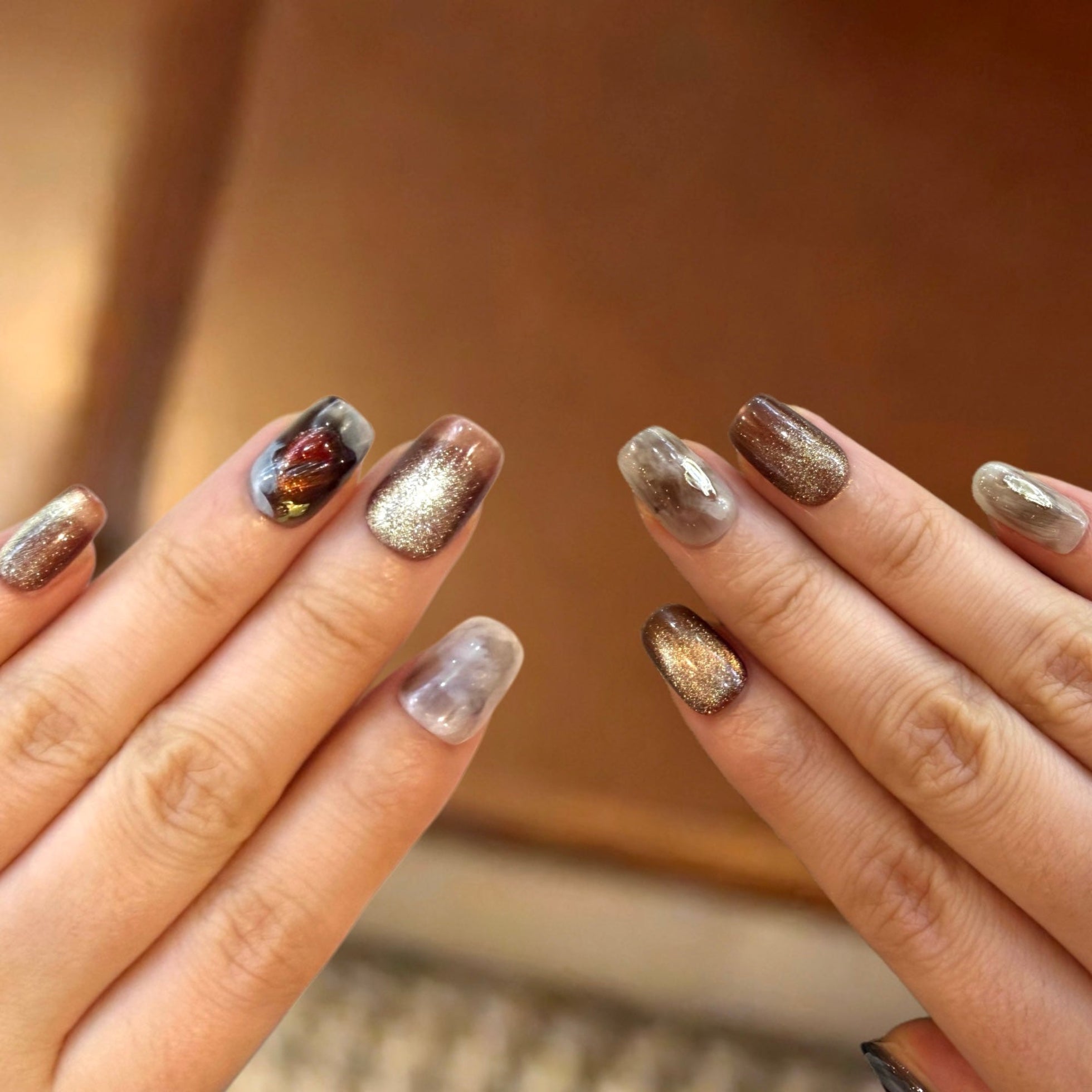 Close-up of hands with glittery nail polish on a blurred background