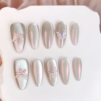Set of silver and pink butterfly nail art designs on a white tray.