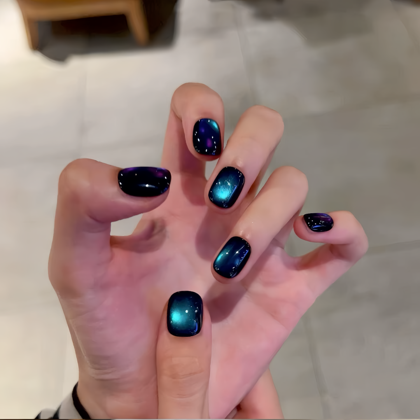 Hand with dark blue and purple gradient nail polish on a neutral background