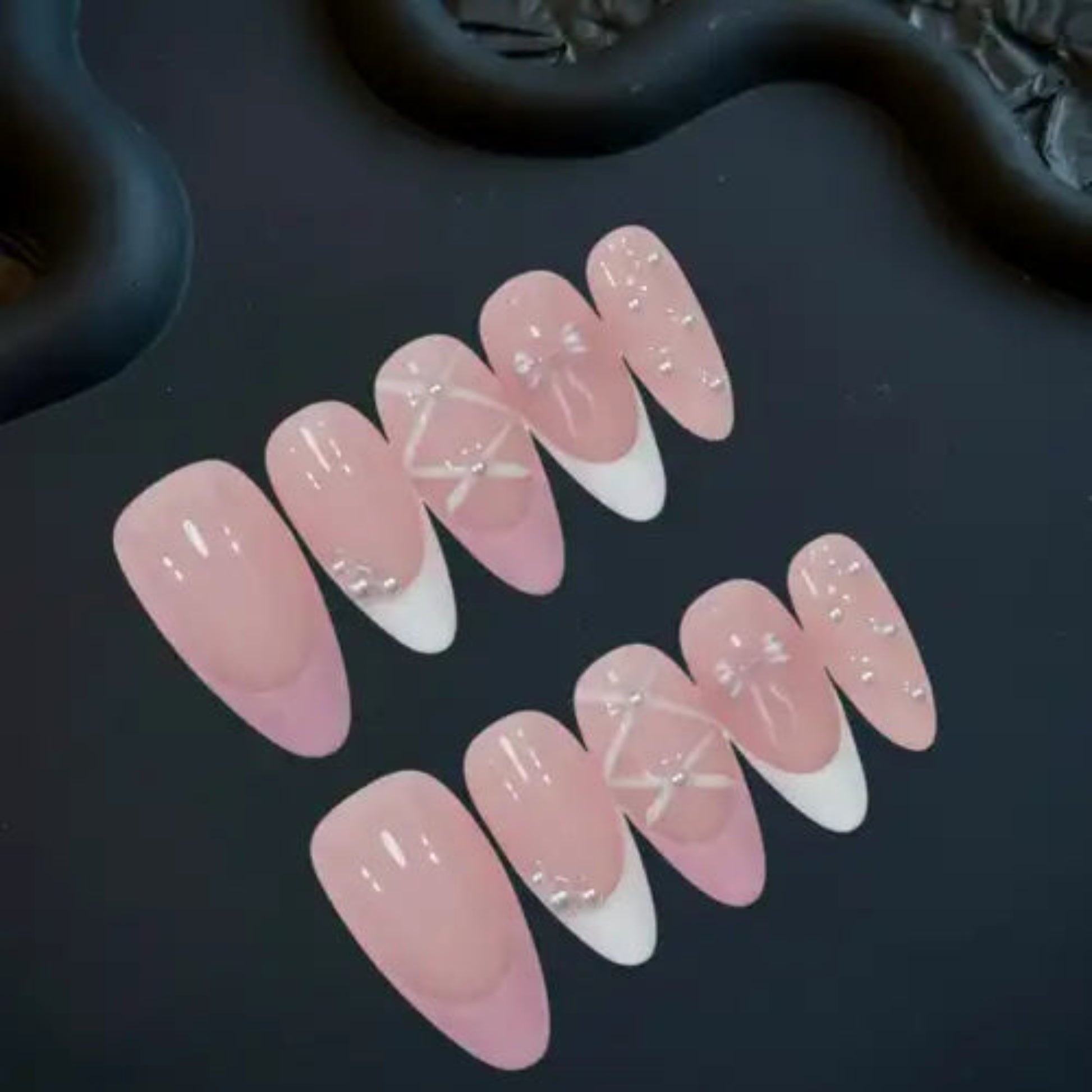 Set of pink and white nail designs on a dark surface