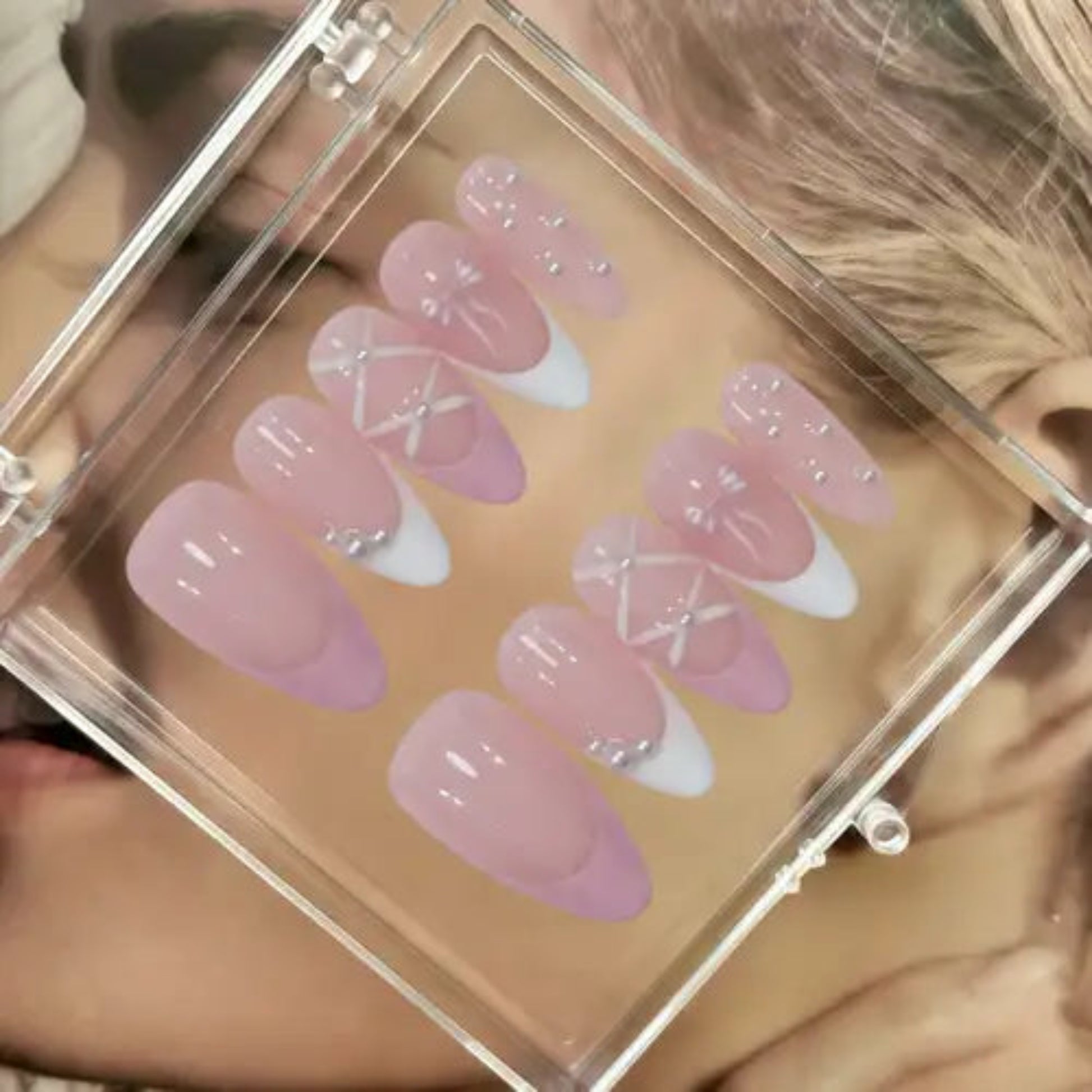 Set of pink and white press-on nails in a clear case.