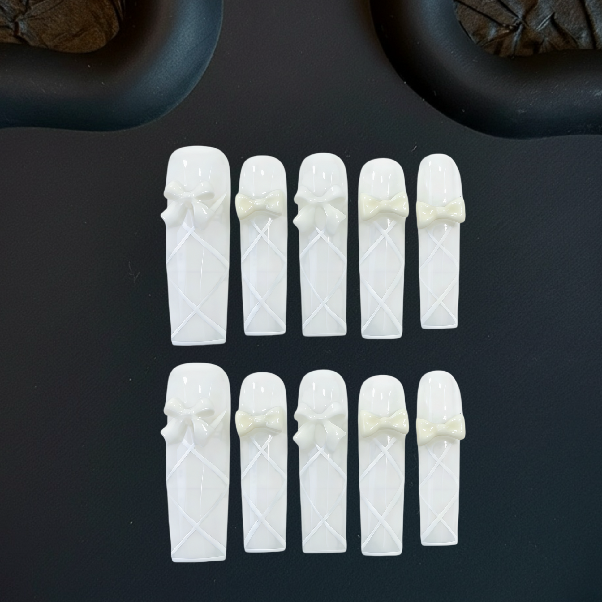 White ceramic tea infusers with decorative bows on a dark surface