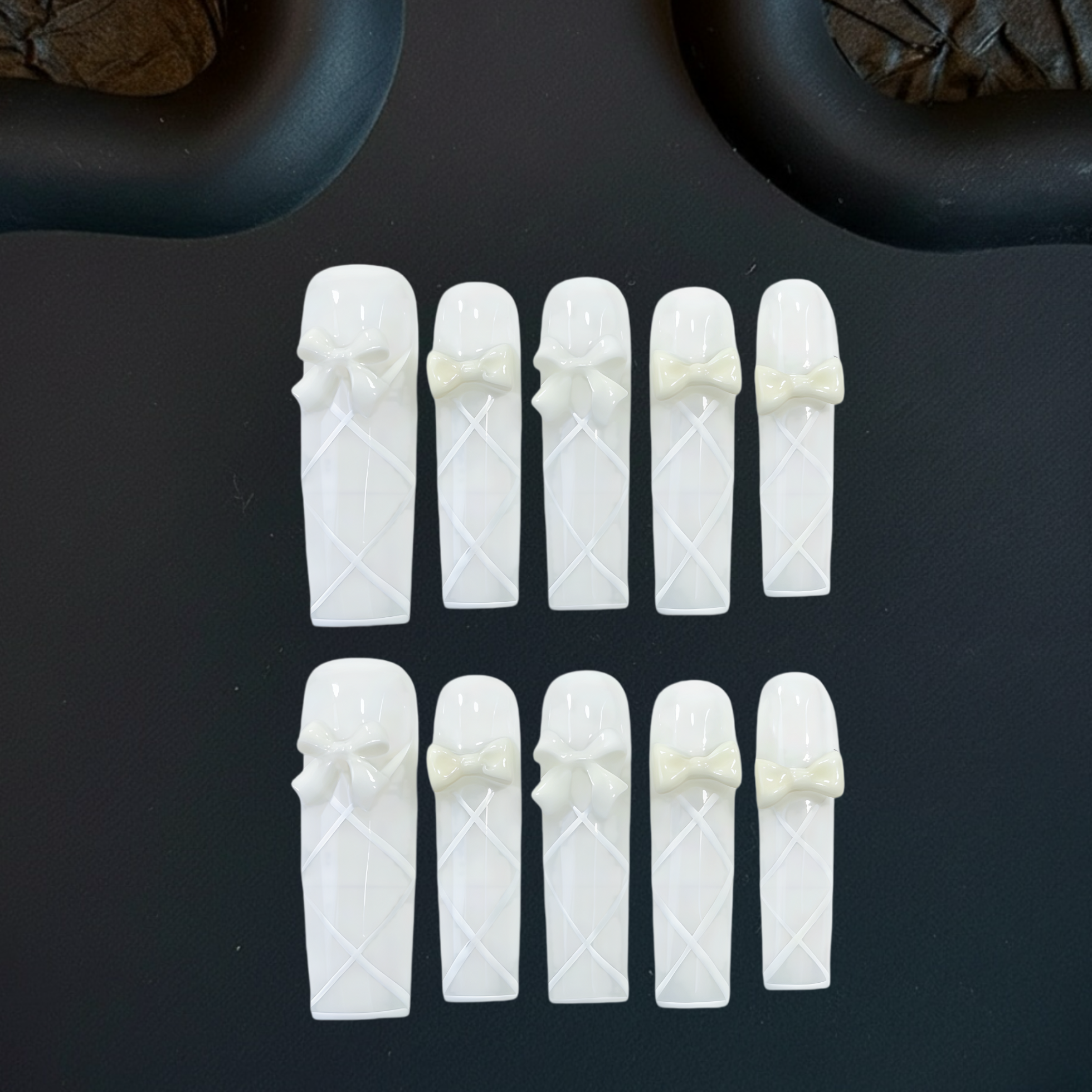 White ceramic tea infusers with decorative bows on a dark surface