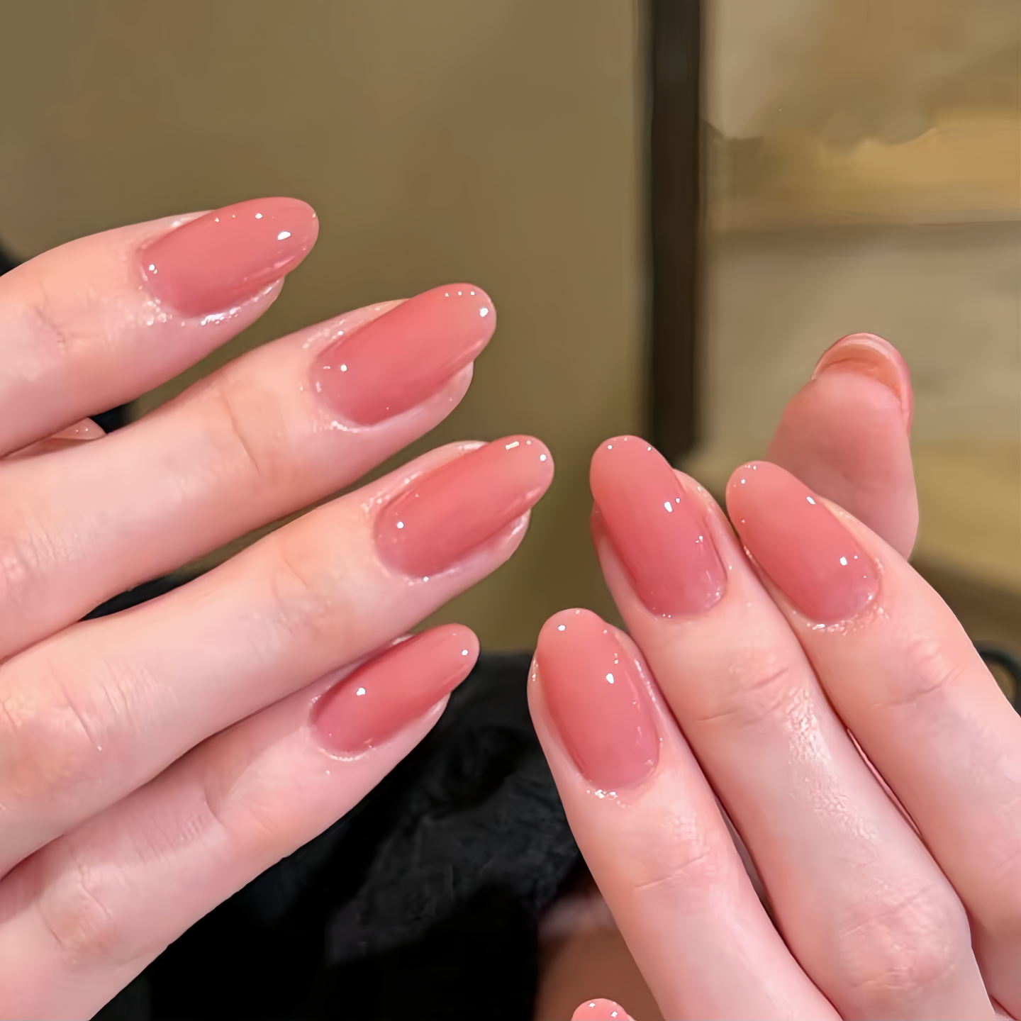Close-up of hands with pink nail polish against a neutral background