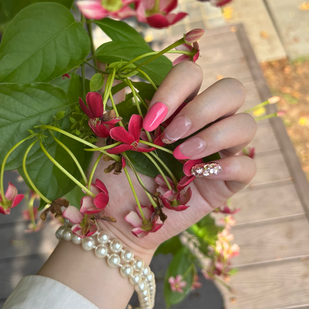Hand holding pink flowers with a blurred outdoor background