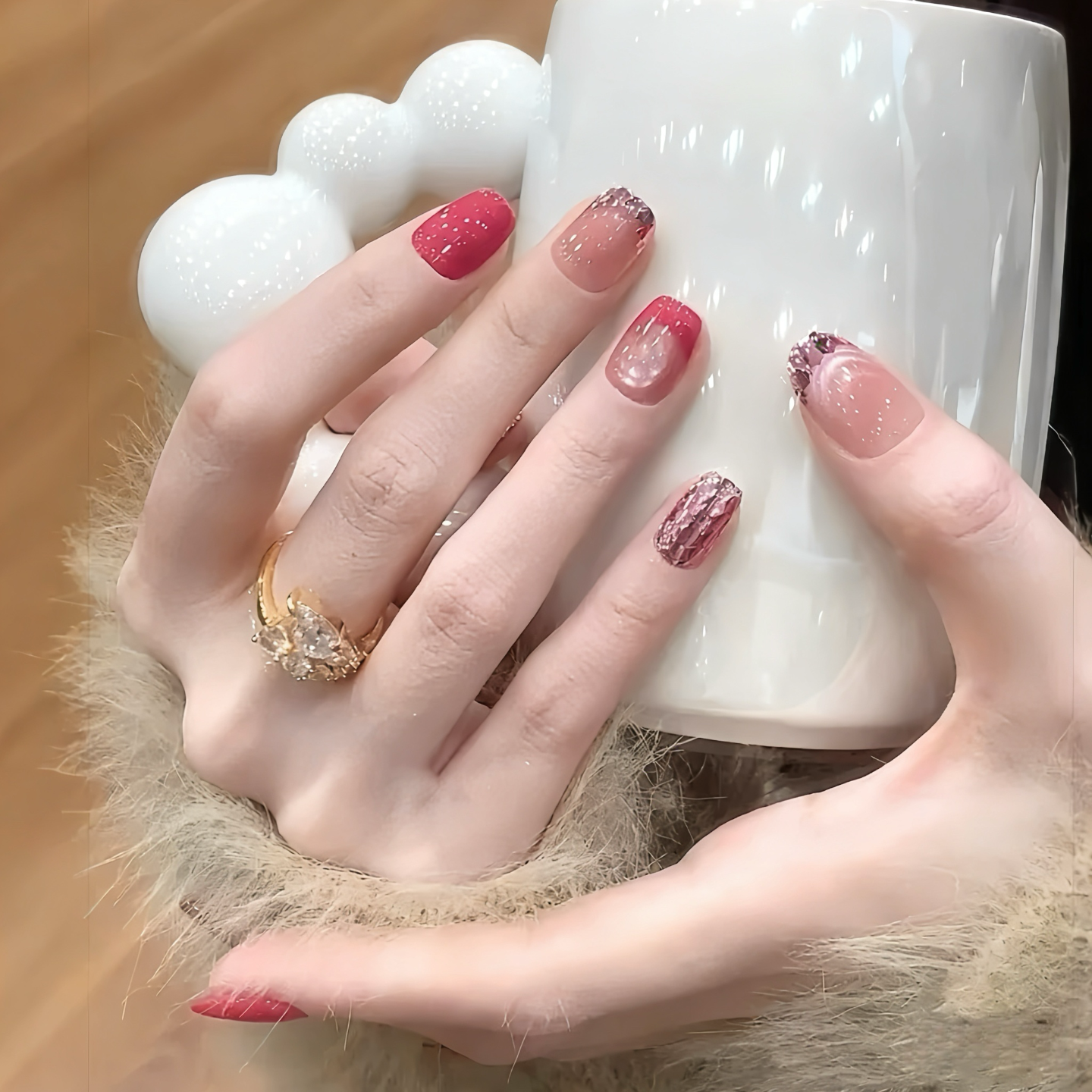 Hand with red and pink nail polish holding a white mug.