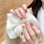 Close-up of a hand with pink glittery nail polish holding a white fluffy object.