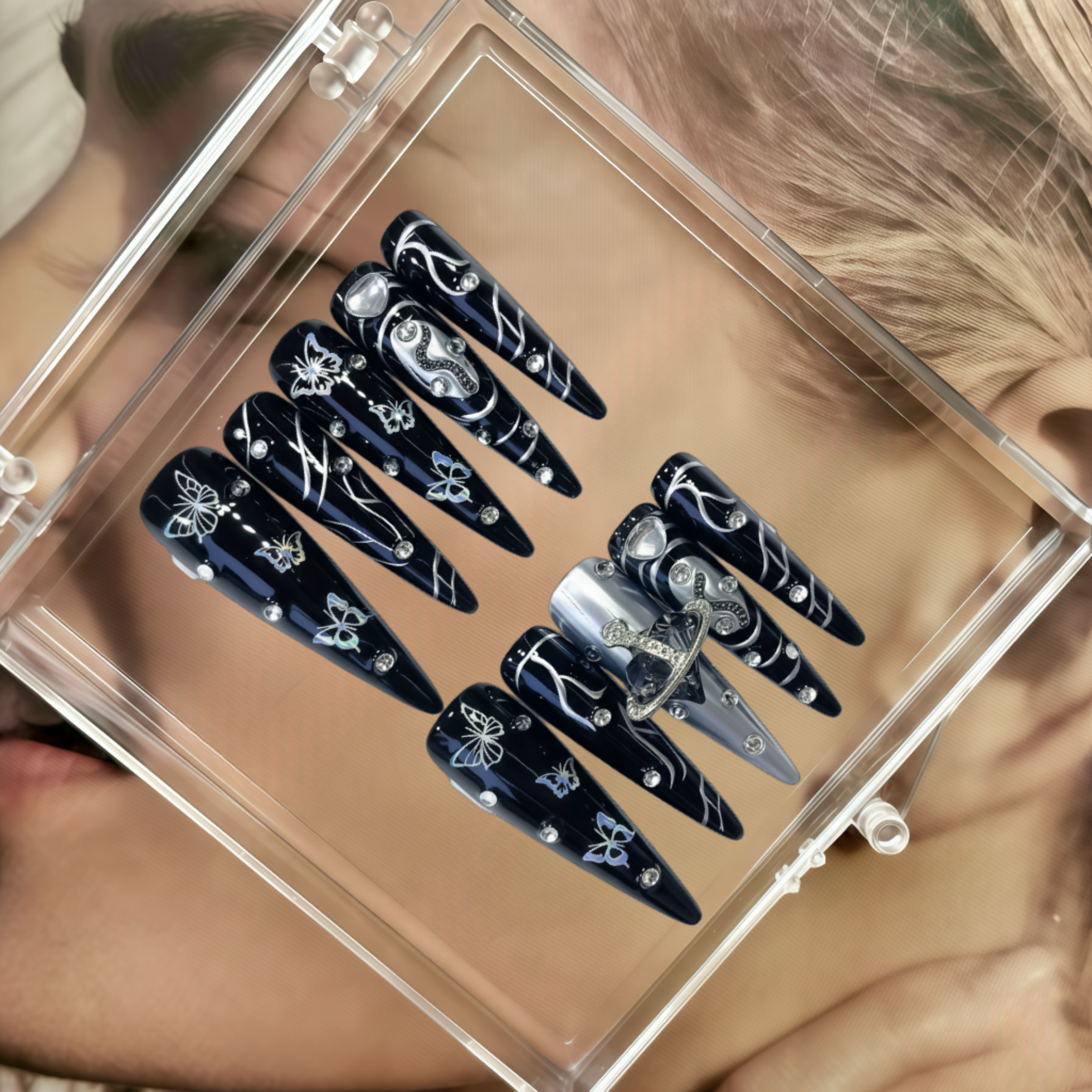 Set of black and silver decorative nails in a clear display case.