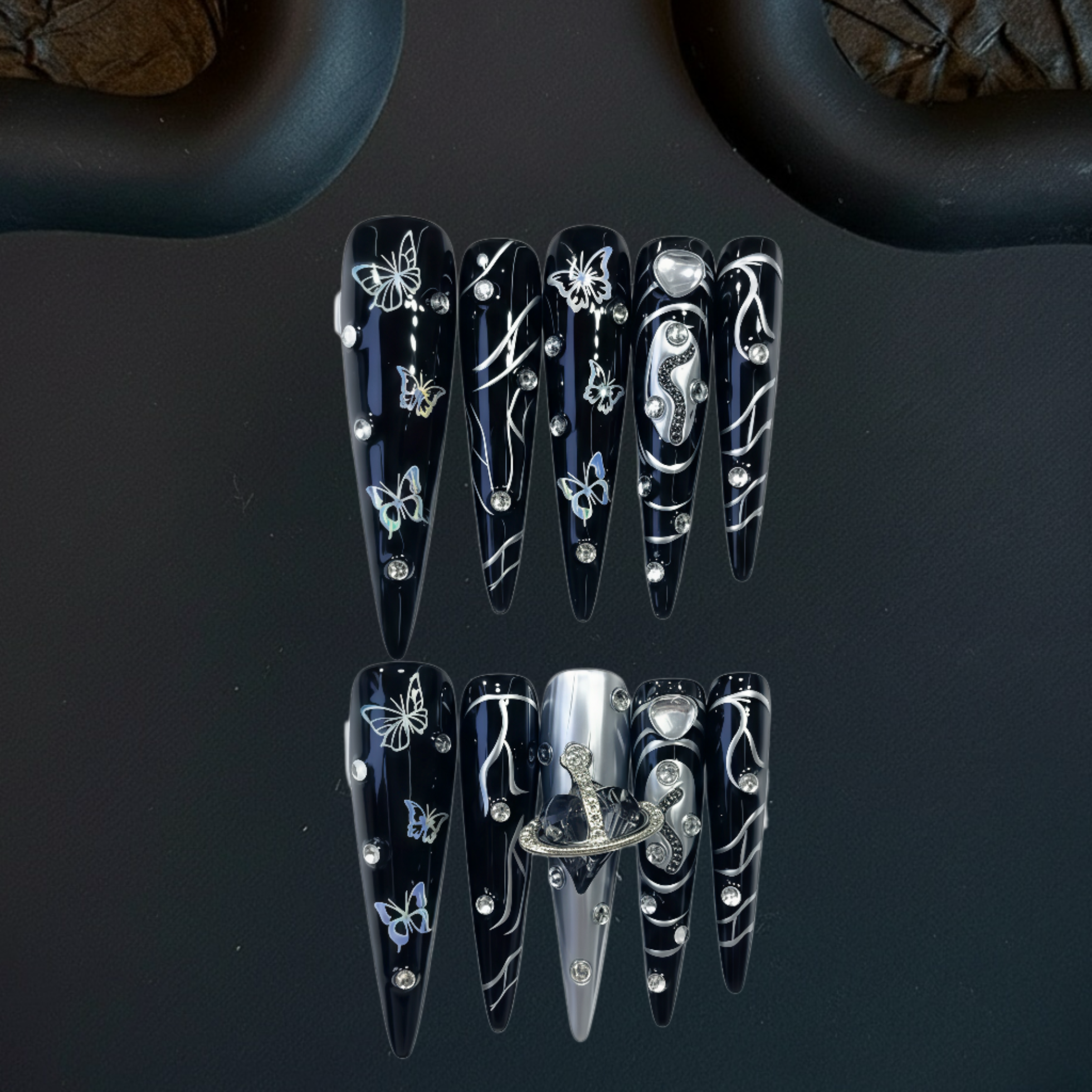 Black nail art designs with silver decorations on a dark background