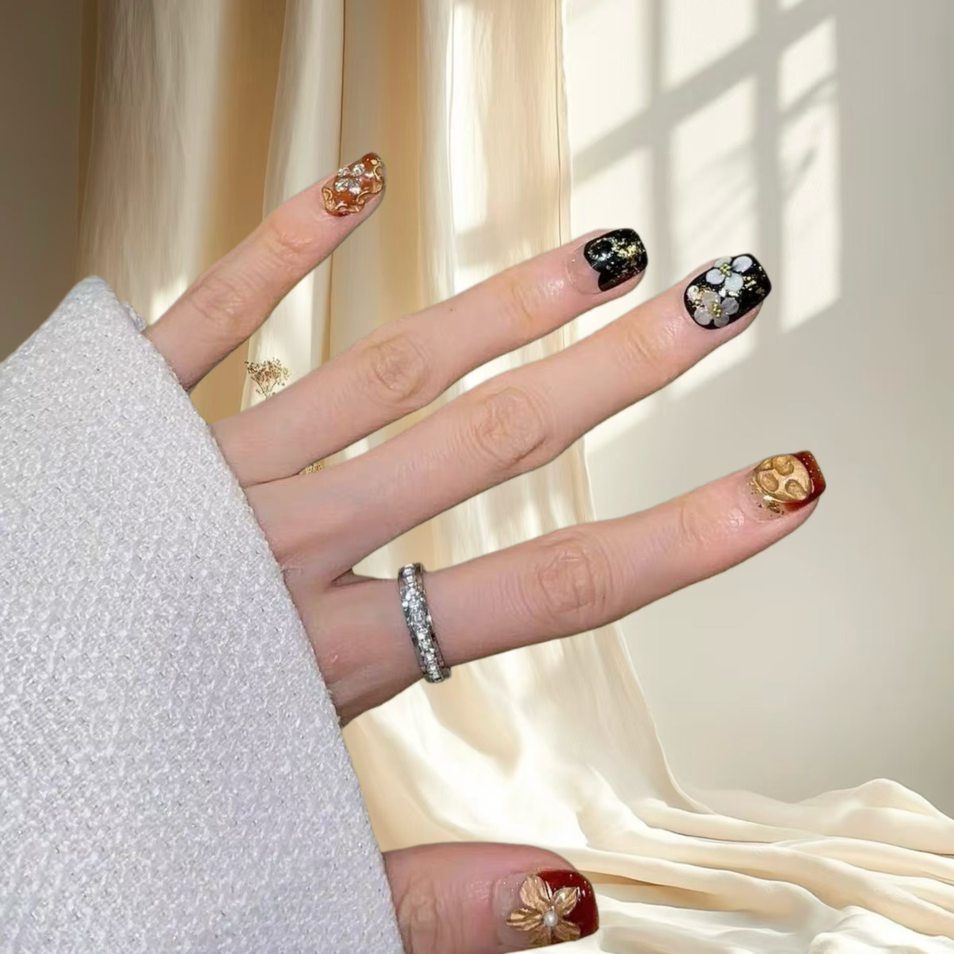 Hand with decorated nails and rings against a light curtain background