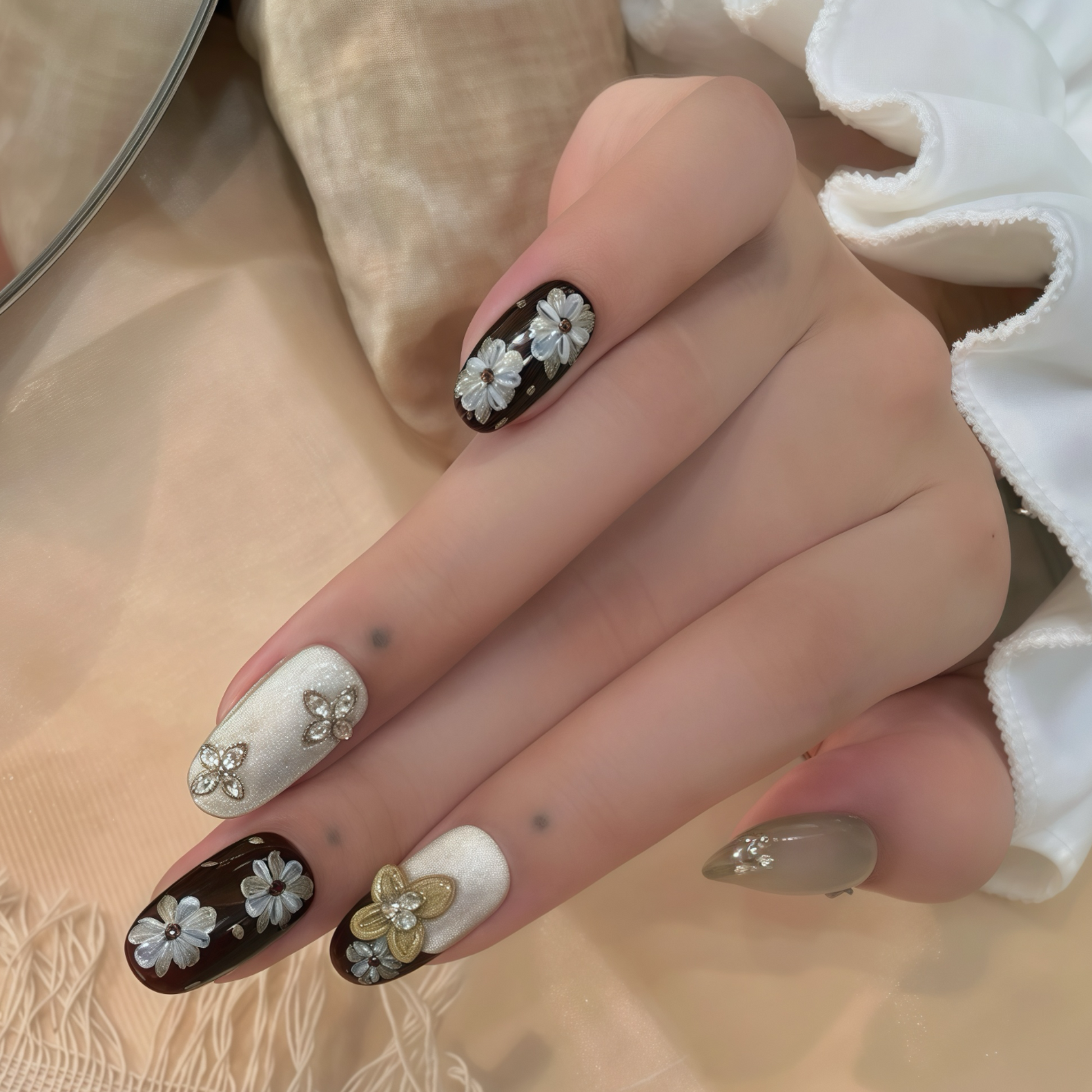 Hand with decorative nails featuring flowers and gold accents on a neutral background