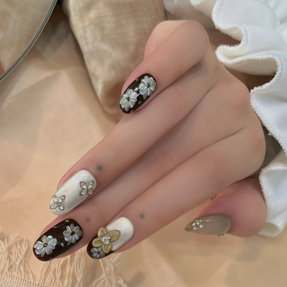 Hand with decorative nails featuring flowers and gold accents on a neutral background