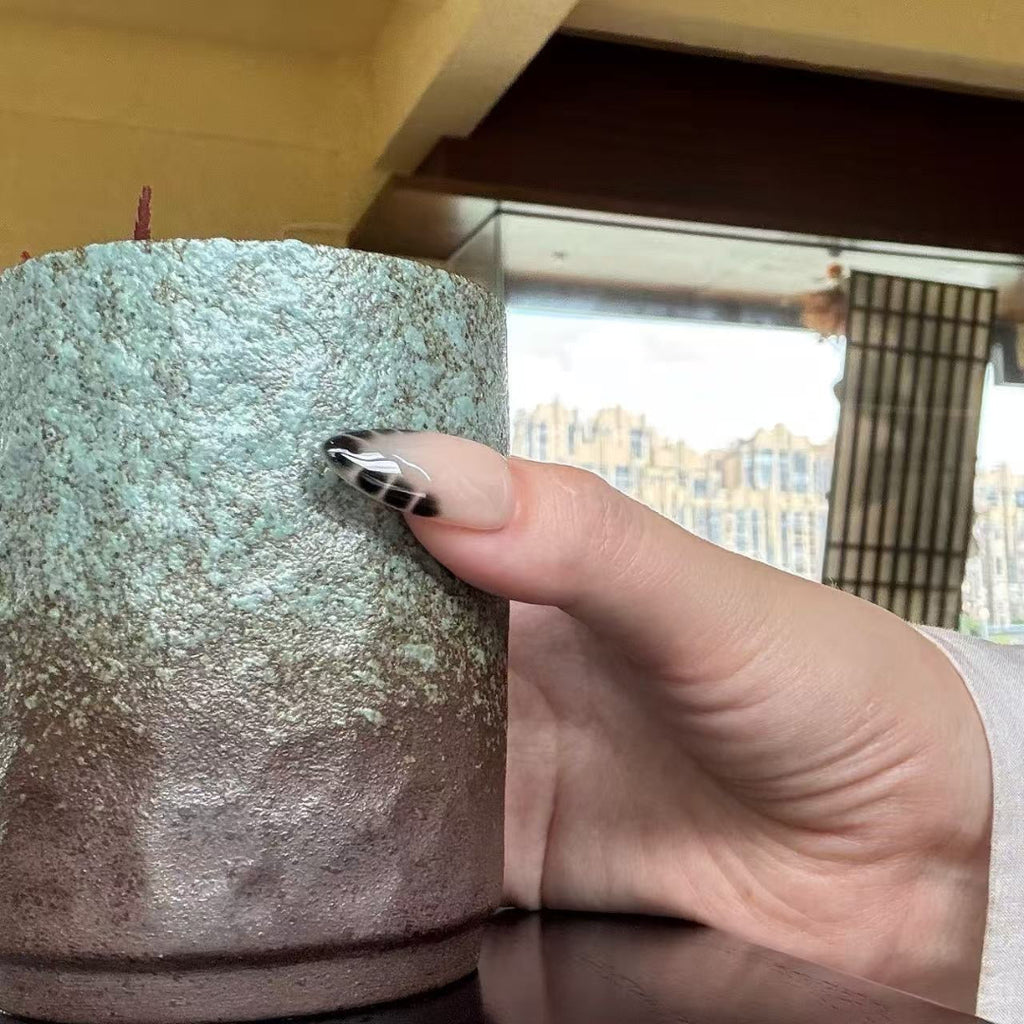 Hand holding a textured candle with a cityscape in the background