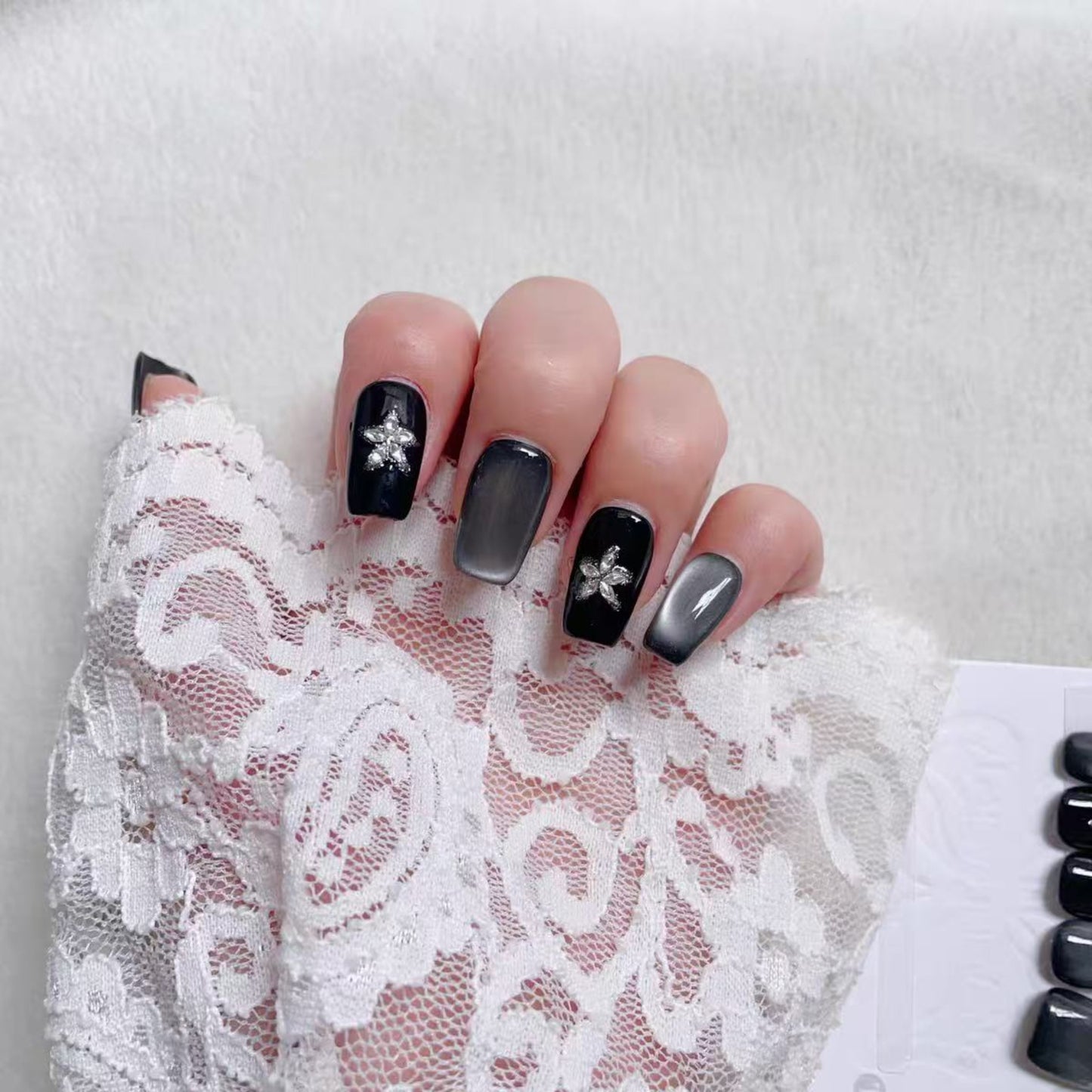 Nails with black and gray design on a lace background