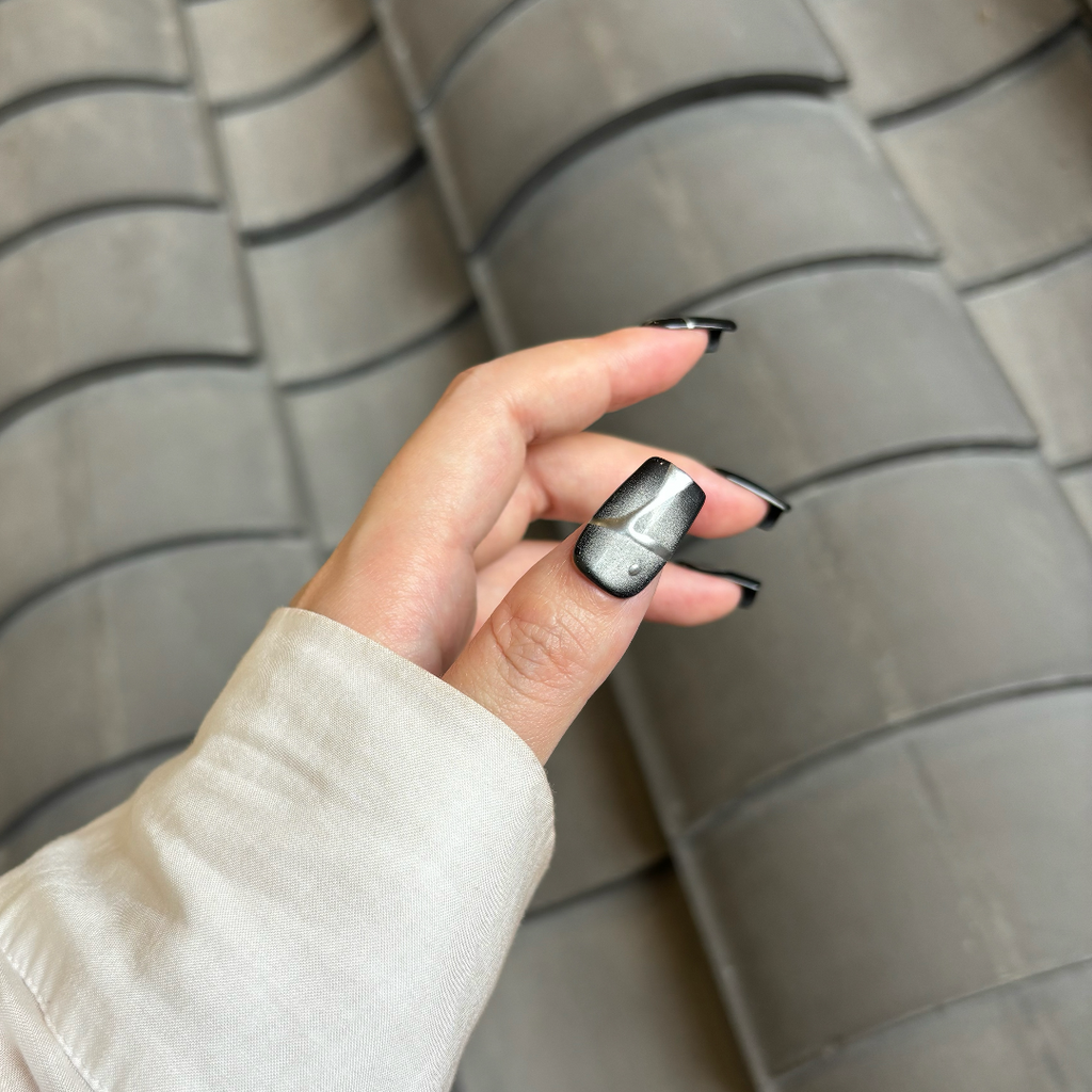 Hand with black nail polish holding a tire against a tiled wall background