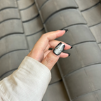 Hand with black nail polish holding a tire against a tiled wall background