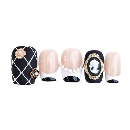 Decorative nail art with black and gold designs on a white background