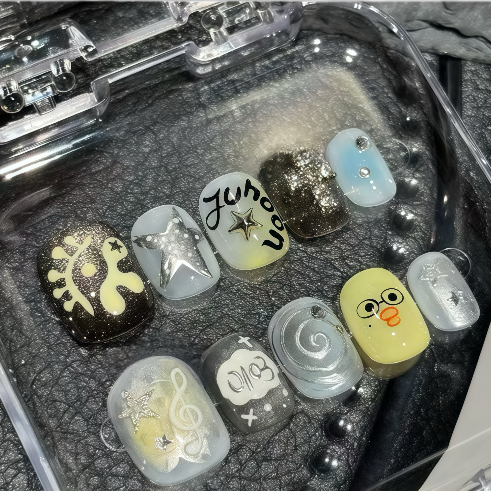 Collection of small decorative items in a clear case on a textured surface