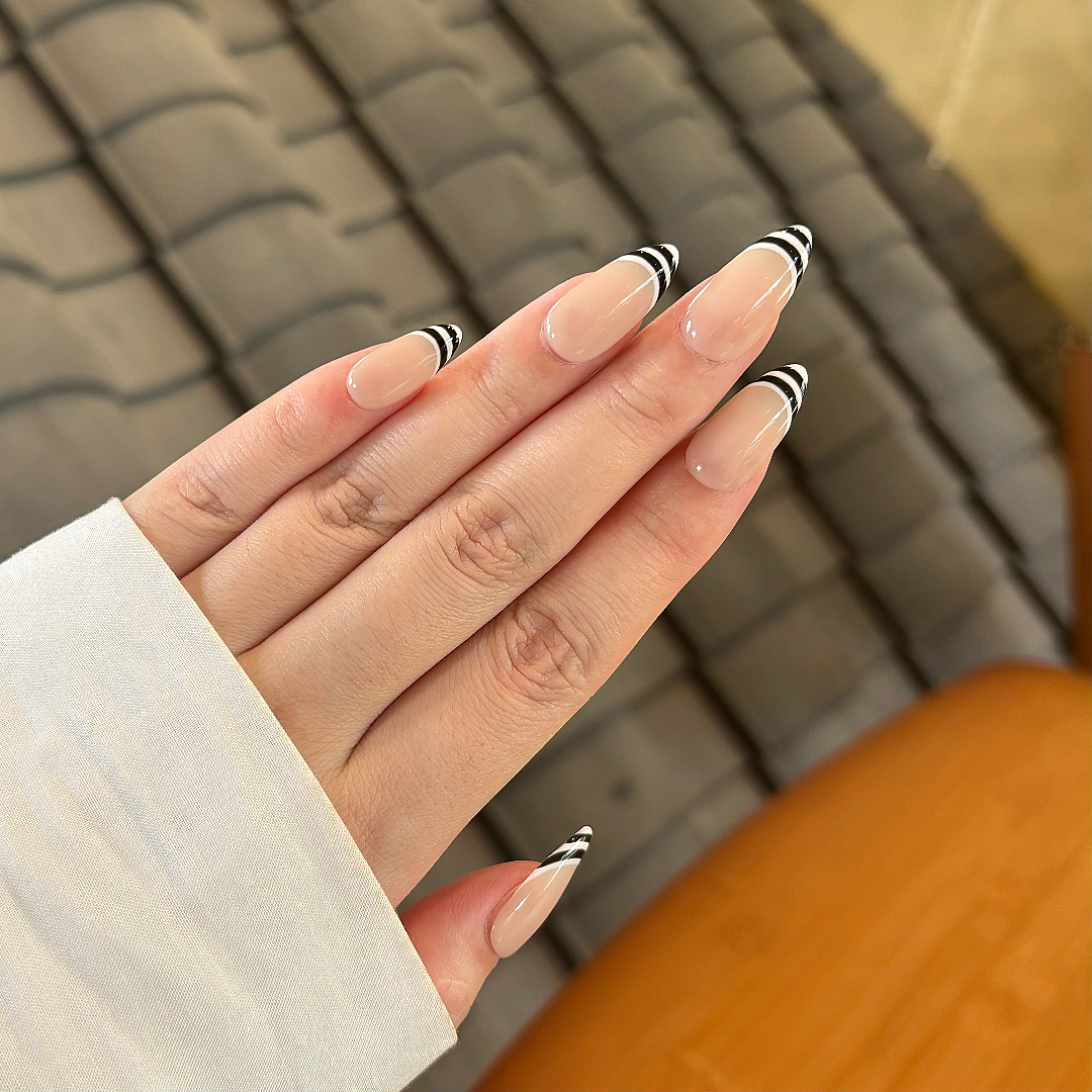 Hand with black and white striped nail design on a blurred background