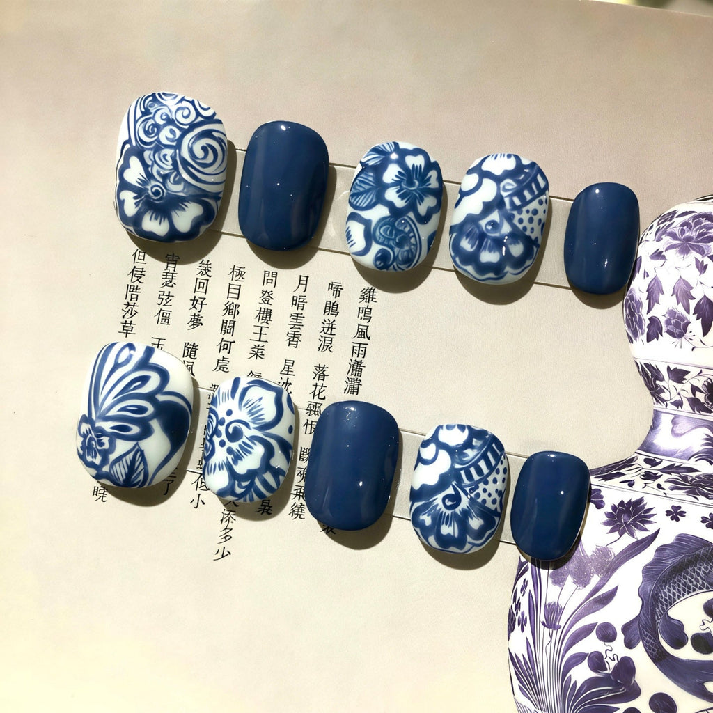 Nails with blue and white floral patterns on a textured surface with text.