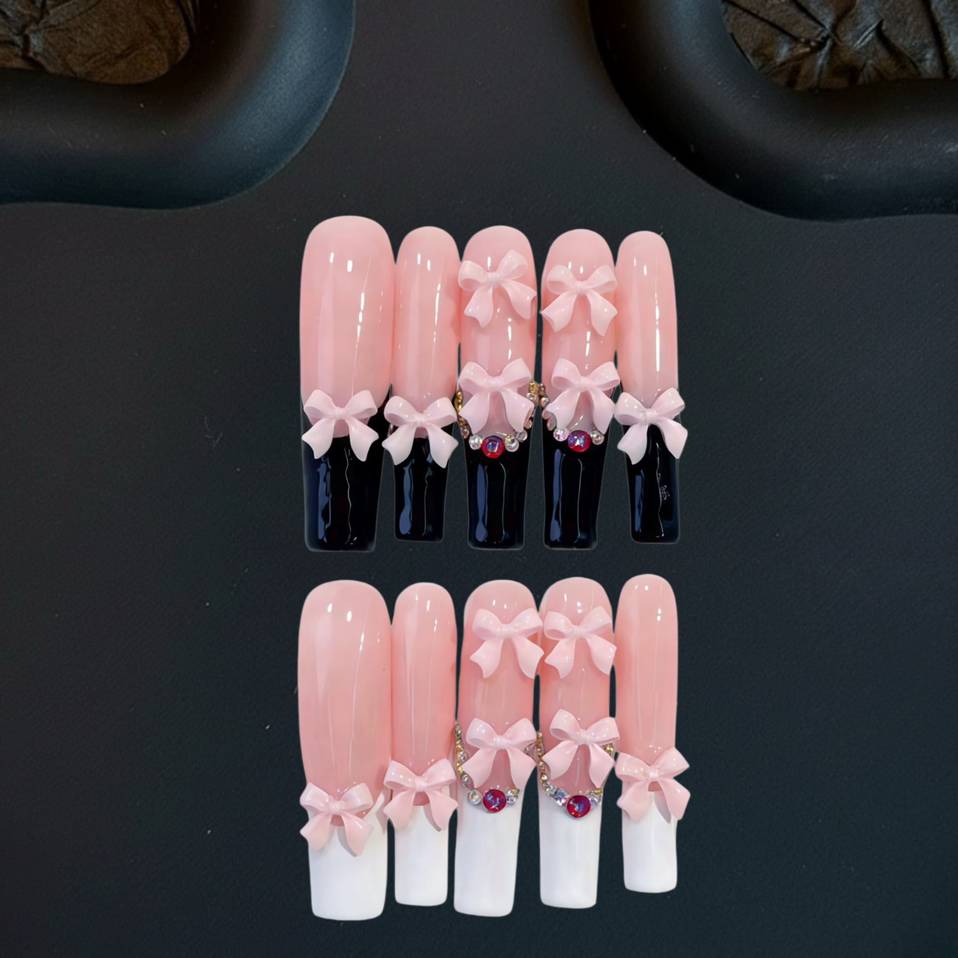 Set of pink and white artificial nails with decorative bows on a black background