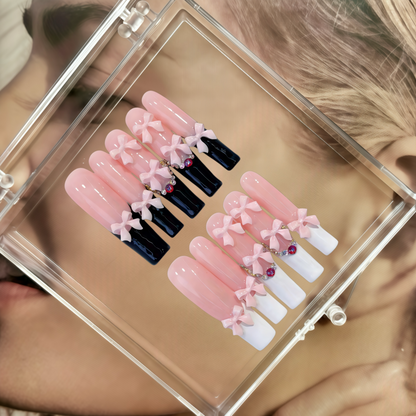 Set of false nails with pink and black designs in a clear display case.
