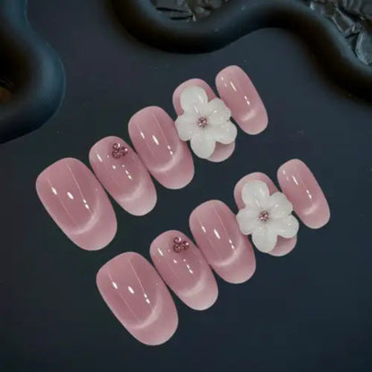 Pink nail art with floral decorations on a dark surface